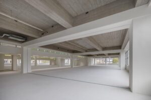Licht en ruim leeg kantoorpand aan de Helmholtzstraat met betonnen plafond en grote ramen.