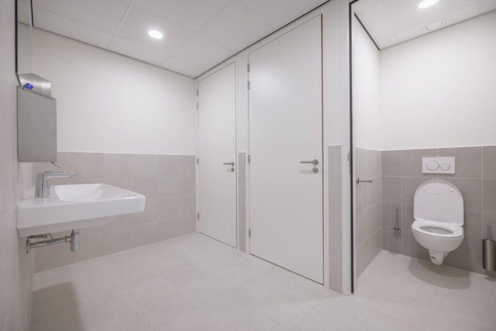 Moderne, goed verlichte toiletruimte met wandcloset, wastafel en twee afgesloten deuren in Helmholtzstraat.