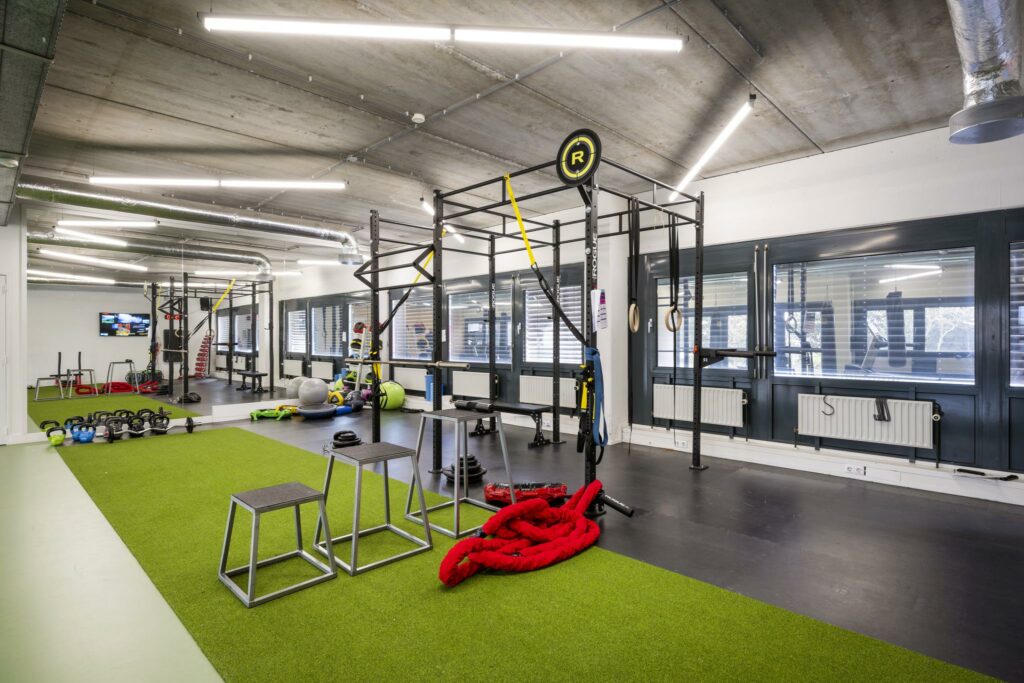 Moderne fitnessruimte in Diemermere met trainingsrekken, gewichten en fitnessaccessoires op een kunstgrasvloer.