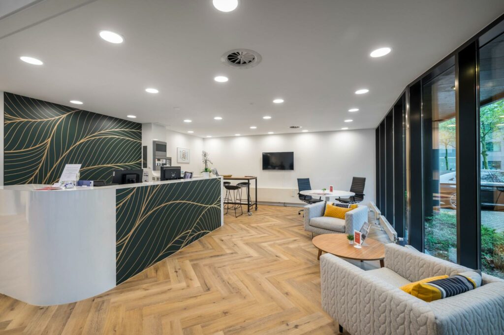 Moderne ontvangstruimte aan de Hullenbergweg met balie, zithoeken en grote raampartijen.