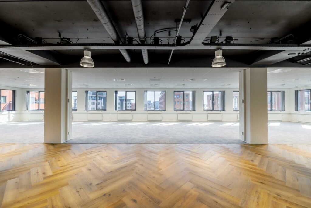 Licht en modern kantoorpand aan de Karspeldreef met visgraat houten vloer en grote ramen rondom.
