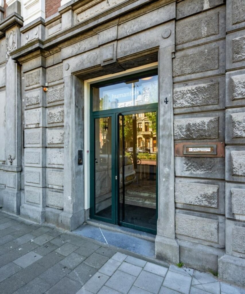 Ingang van het gebouw aan de Sarphatistraat 4 in Amsterdam met de naam 'Humanitas' op de glazen deur.