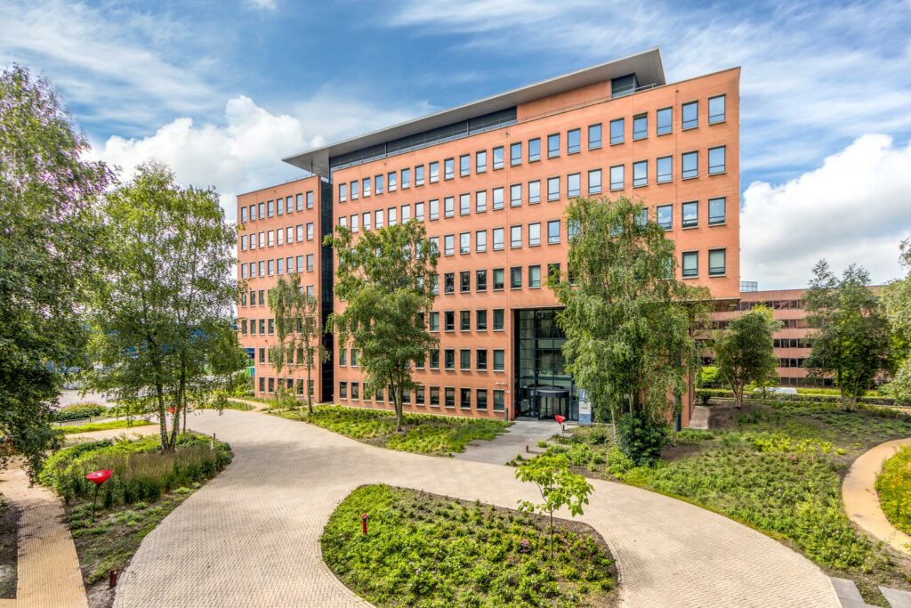 Modern kantoorgebouw aan de Hullenbergweg omringd door groen en wandelpaden.