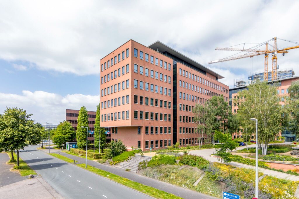 Modern kantoorpand aan de Hullenbergweg in Amsterdam-Zuidoost met rode bakstenen gevel en omliggende groenvoorziening.