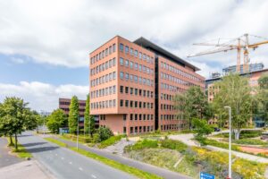 Modern kantoorpand aan de Hullenbergweg in Amsterdam-Zuidoost met rode bakstenen gevel en omliggende groenvoorziening.
