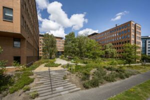 Kantoorgebouwen aan de Hullenbergweg met een groene binnentuin en looppaden onder een blauwe hemel.