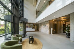 Moderne entreehal van een kantoorgebouw aan de Hullenbergweg met zitgedeelte, receptie en liften.