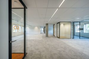 Moderne, lege kantoorruimte aan de Hullenbergweg met glazen vergaderruimtes en neutraal tapijt.