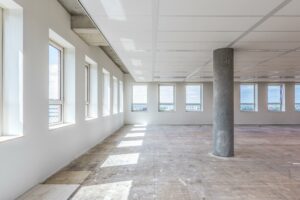 Leeg kantoorruimte aan de Hullenbergweg met grote ramen en betonnen vloer.
