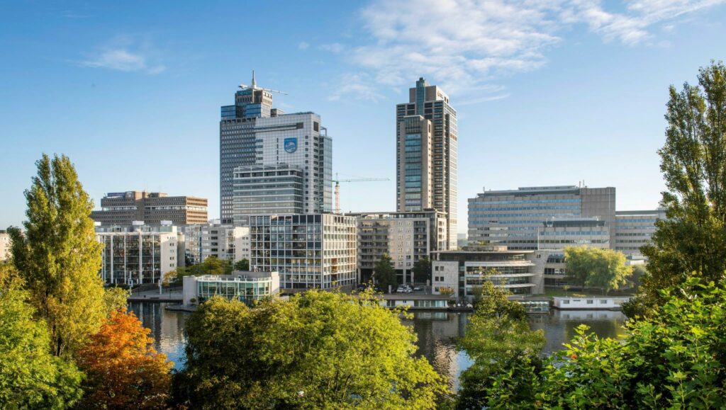 Skyline van Amstelplein in Amsterdam met moderne kantoorgebouwen en een rivier op de voorgrond.