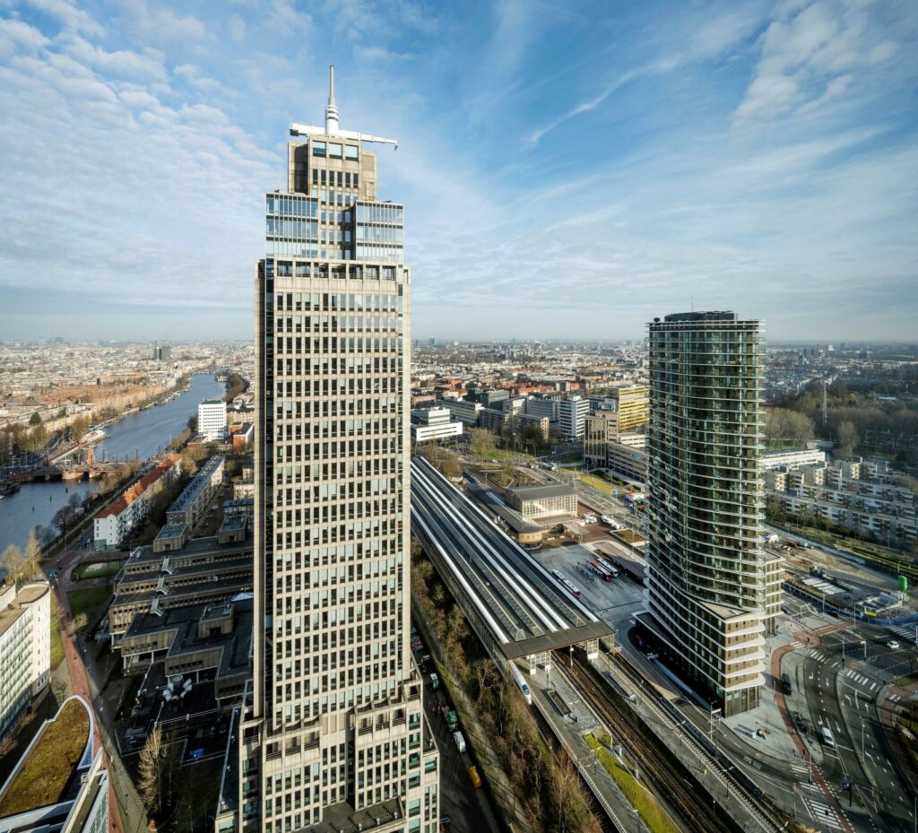 Luchtfoto van het Amstelplein in Amsterdam met hoge kantoorgebouwen en het Amstelstation op de voorgrond.