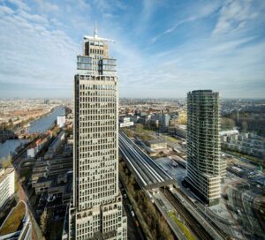 Luchtfoto van het Amstelplein in Amsterdam met hoge kantoorgebouwen en het Amstelstation op de voorgrond.