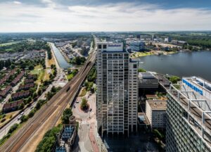 Luchtfoto van het Amstelplein in Amsterdam met het Rabobank-gebouw op de voorgrond en zicht op spoorlijnen en waterpartijen.