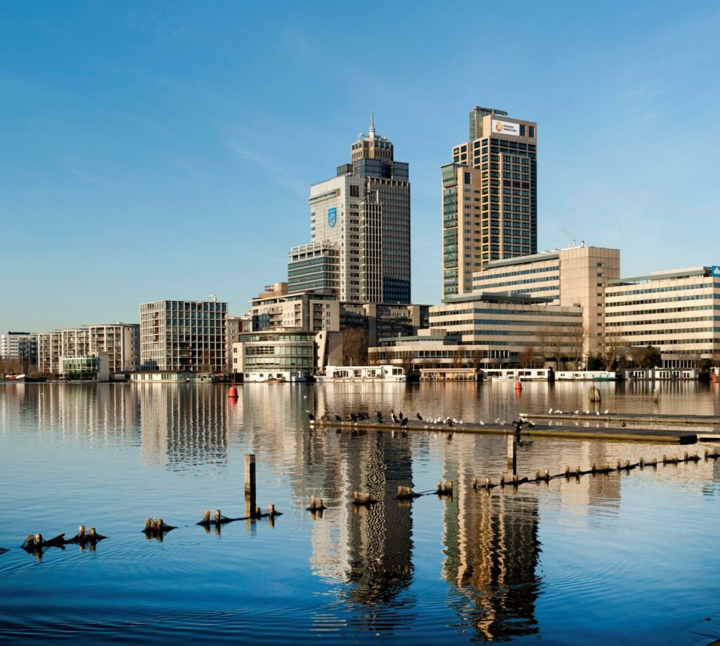 Skyline van Amstelplein in Amsterdam met moderne kantoorgebouwen weerspiegeld in de Amstel.