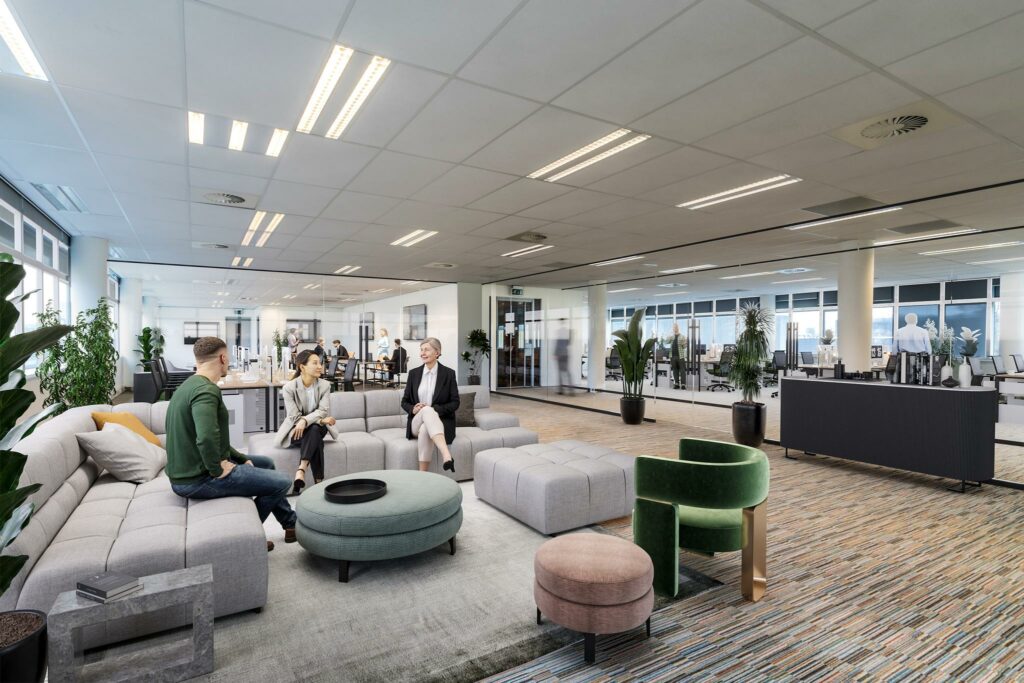Moderne kantoorlounge aan de Lemelerbergweg met drie personen in gesprek en werkplekken op de achtergrond.