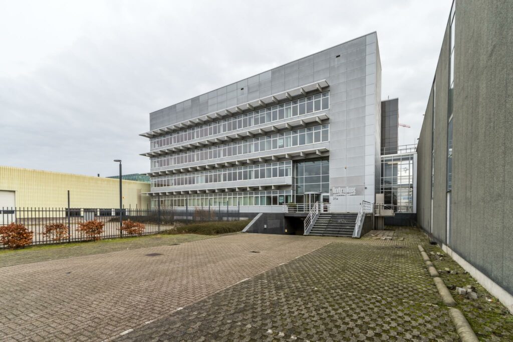 Modern kantoorgebouw aan de Lemelerbergweg 31a met glazen gevel en metalen trappen aan de voorzijde.
