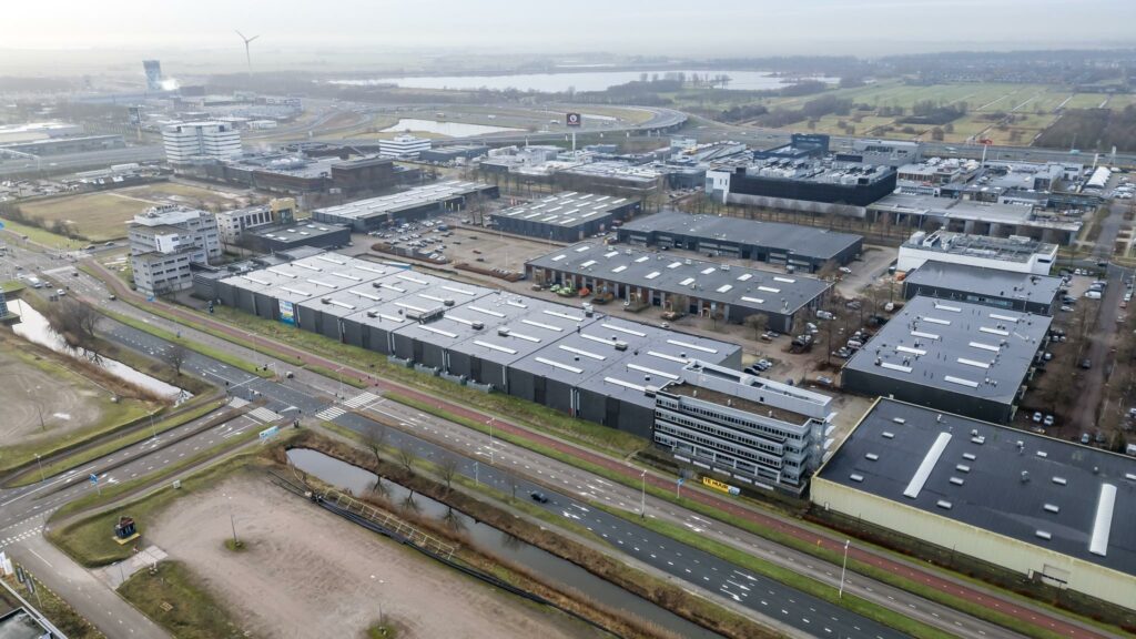 Luchtfoto van het bedrijventerrein aan de Lemelerbergweg in Amsterdam, met moderne bedrijfspanden, wegen en waterwegen zichtbaar.