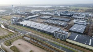 Luchtfoto van het bedrijventerrein aan de Lemelerbergweg in Amsterdam, met moderne bedrijfspanden, wegen en waterwegen zichtbaar.