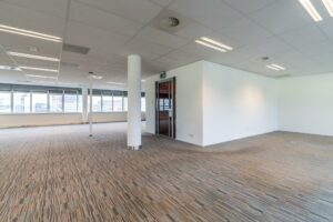 Leeg kantoorpand aan de Lemelerbergweg met systeemplafond, glazen deur en grote ramen met uitzicht op de stad.