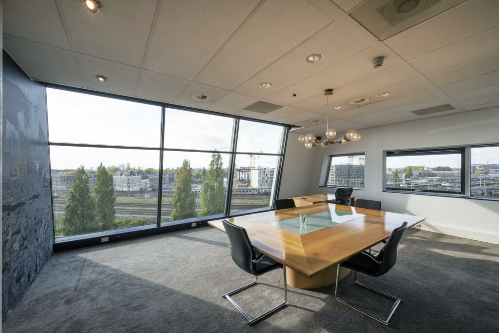 Vergaderruimte met grote ramen en uitzicht op het spoor bij Rietlandpark in Amsterdam.