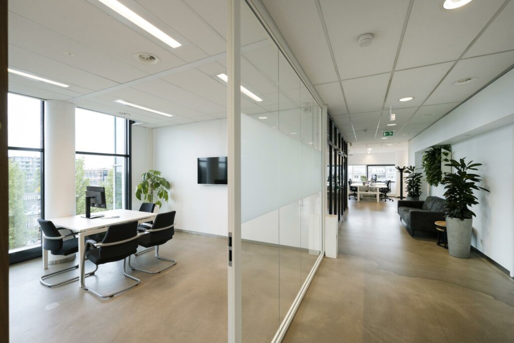 Moderne kantoorruimte in Rietlandpark met vergaderruimte, glazen wanden en een open werkruimte met veel natuurlijk licht.