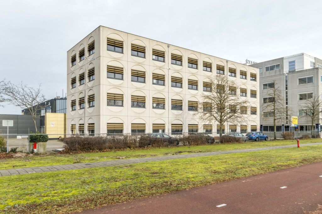 Kantoorgebouw aan de Laarderhoogtweg met opvallende ronde raamvormen en parkeergelegenheid op de voorgrond.