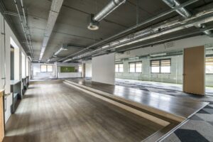 Moderne, industriële kantoorruimte aan de Laarderhoogtweg met verhoogd houten podium en glazen wanden.