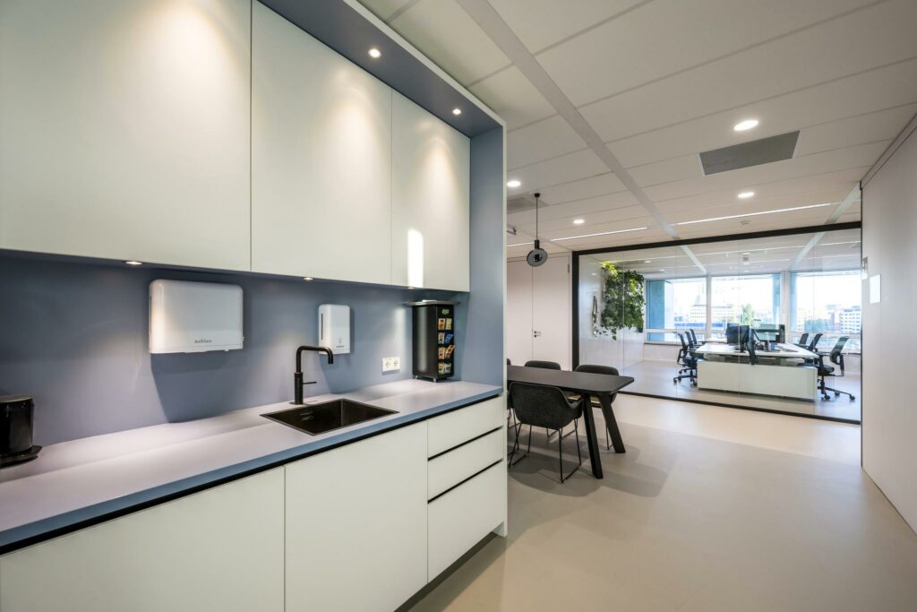 Moderne kantoorruimte aan de Paalbergweg met een strakke pantry, vergadertafel en zicht op een glazen vergaderruimte met uitzicht op de stad.