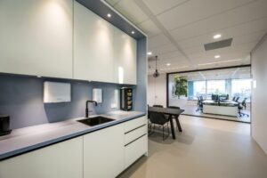 Moderne kantoorruimte aan de Paalbergweg met een strakke pantry, vergadertafel en zicht op een glazen vergaderruimte met uitzicht op de stad.