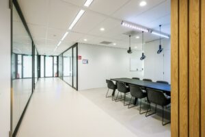 Moderne vergaderruimte aan de Paalbergweg met glazen wanden, zwarte stoelen en hanglampen.