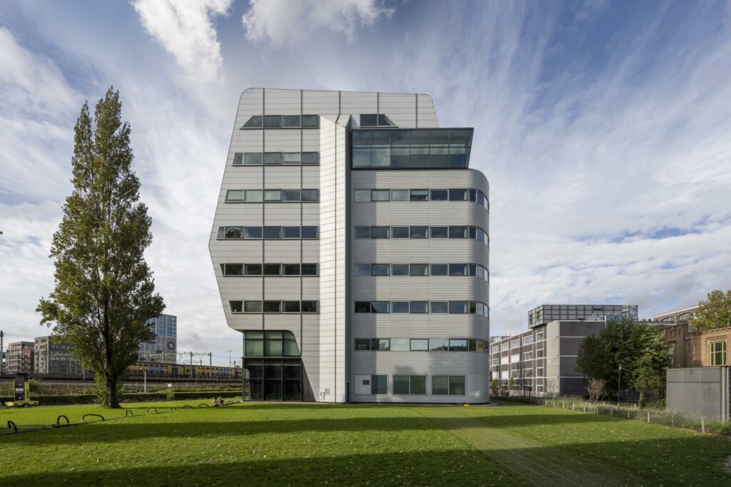 Modern kantoorgebouw Rietlandpark met opvallende architectuur, gelegen aan een grasveld in een stedelijke omgeving.