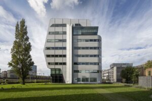 Modern kantoorgebouw Rietlandpark met opvallende architectuur, gelegen aan een grasveld in een stedelijke omgeving.