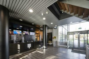 Moderne entreehal van het Rietlandpark met receptiebalie, trap en glazen draaideur naar buiten.