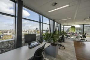 Modern kantoorinterieur in Rietlandpark met grote ramen, werkplekken en groene planten.