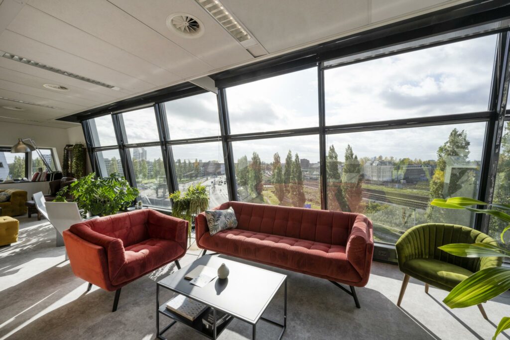 Licht en modern interieur met comfortabele zitplekken en uitzicht op Rietlandpark en het spoorwegennet buiten.