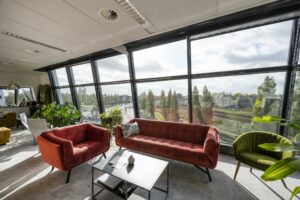 Licht en modern interieur met comfortabele zitplekken en uitzicht op Rietlandpark en het spoorwegennet buiten.