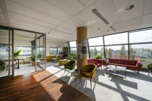 Lichte en modern ingerichte lounge- en werkruimte in kantoorgebouw Rietlandpark met uitzicht op het spoor en omliggende natuur.