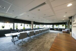 Vergaderruimte in Rietlandpark met lange tafel, moderne stoelen en hangende planten.