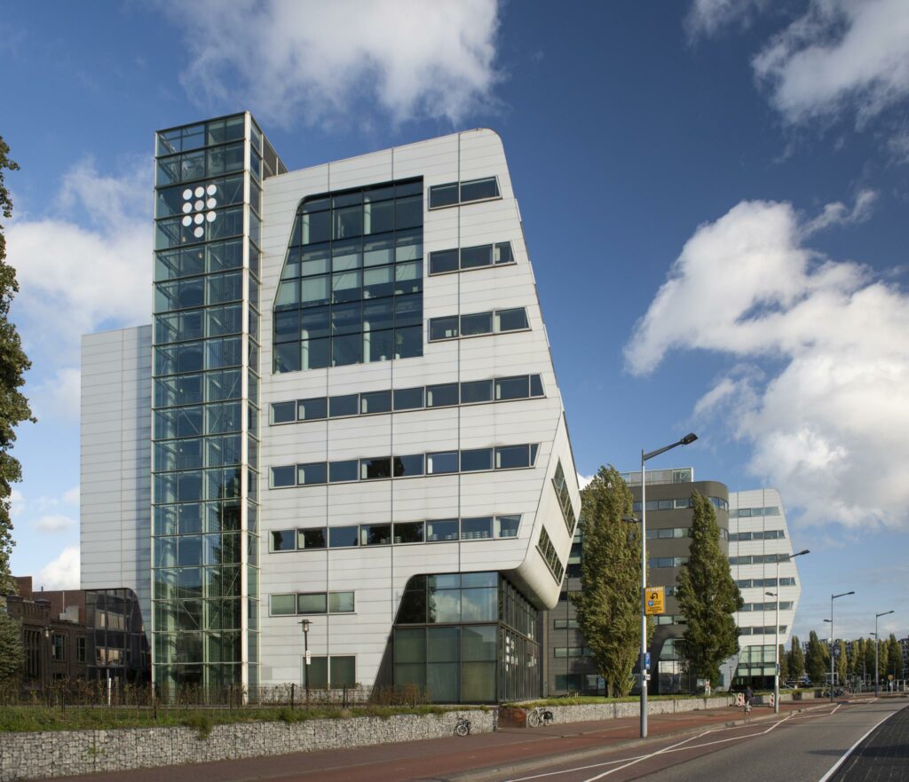 Modern kantoorgebouw aan het Rietlandpark in Amsterdam met een opvallende schuine gevel en glazen trappenhuis.