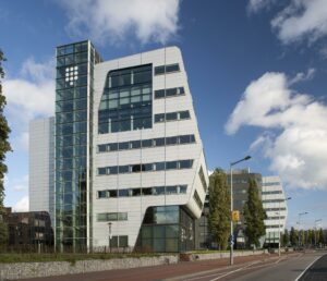 Modern kantoorgebouw aan het Rietlandpark in Amsterdam met een opvallende schuine gevel en glazen trappenhuis.