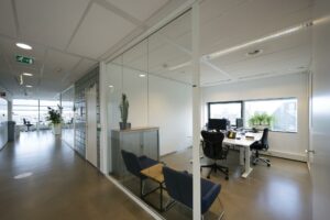 Modern kantoorinterieur in Rietlandpark met glazen wanden, bureaus, stoelen en uitzicht op de stad.