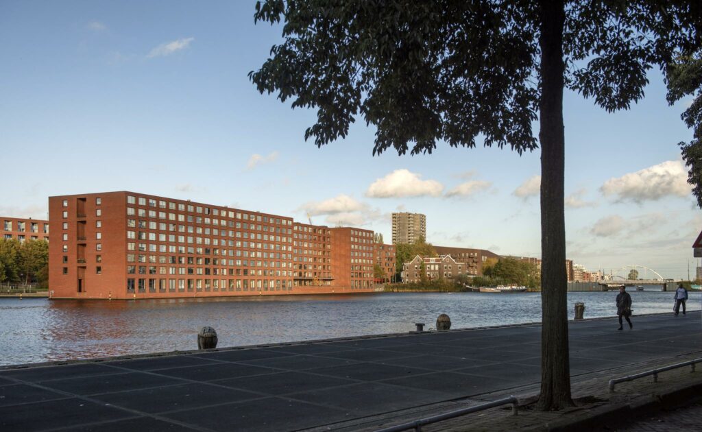 Uitzicht op het Rietlandpark met moderne bakstenen appartementsgebouwen aan het water in Amsterdam.