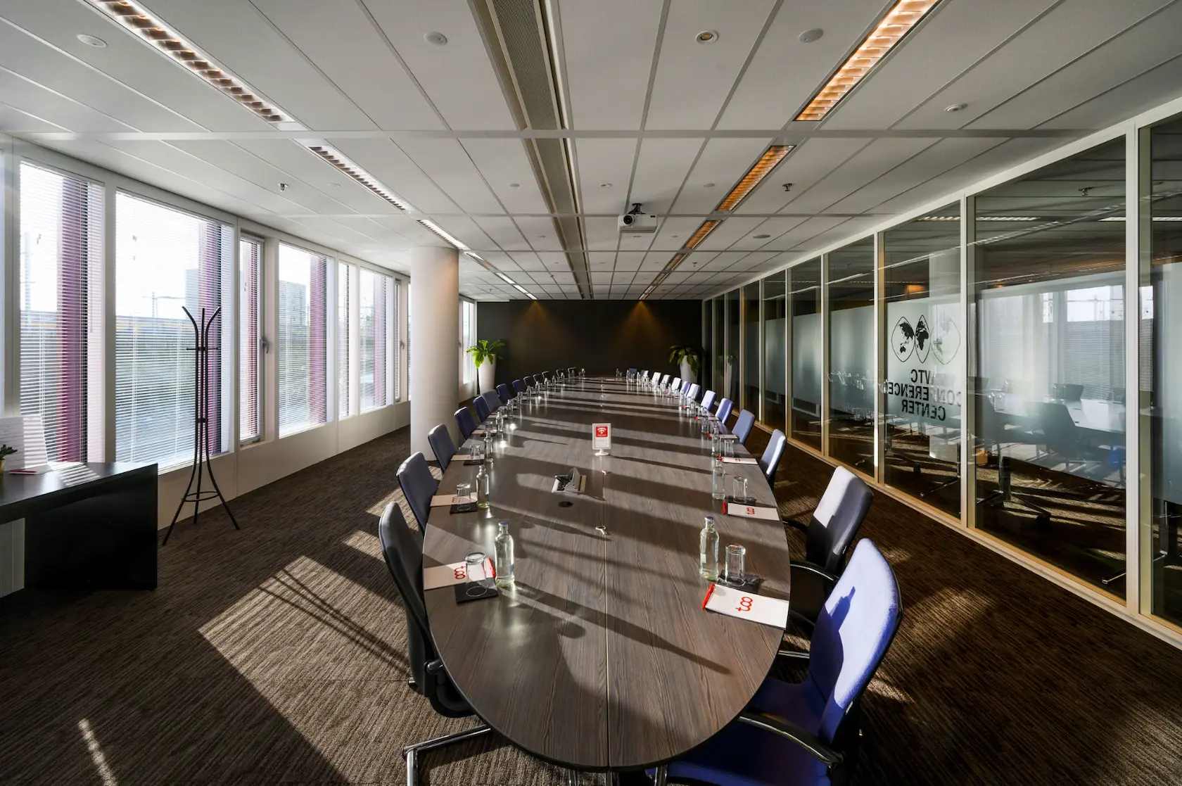 Modern conference room at P.J. Oudweg with a long oval table, set up for a meeting with chairs, notepads, and water bottles.