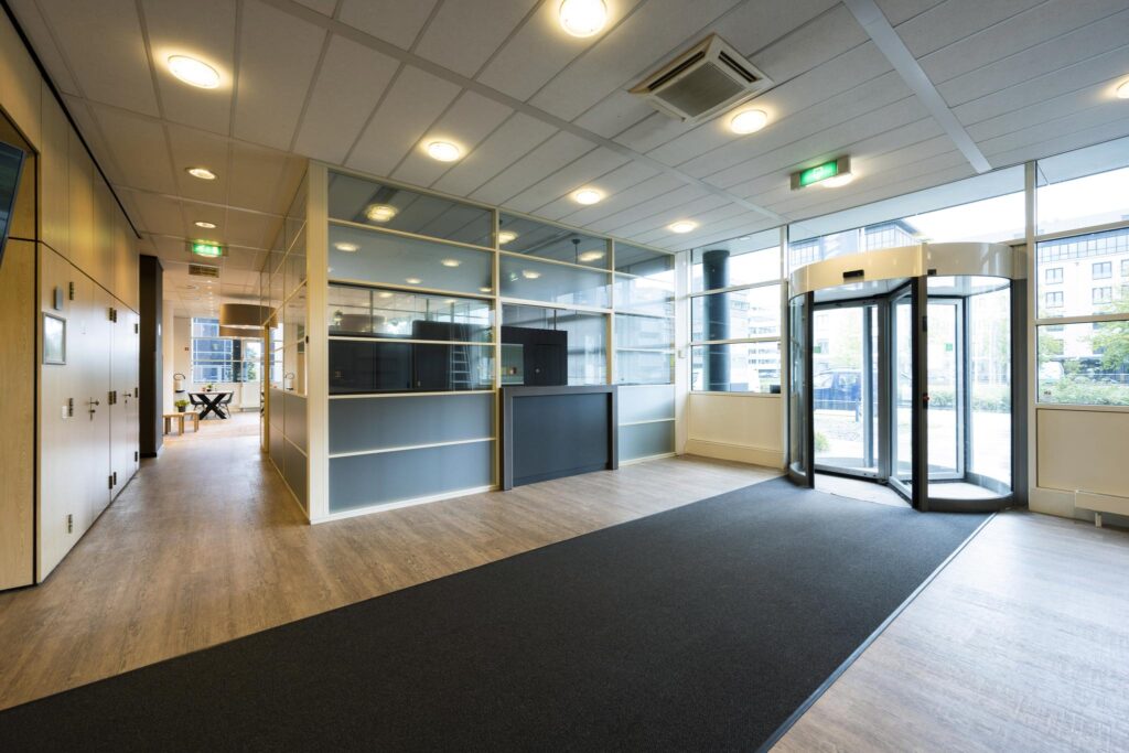 Moderne en lichte entreehal van een kantoorgebouw aan de Paasheuvelweg met een draaideur en balie.