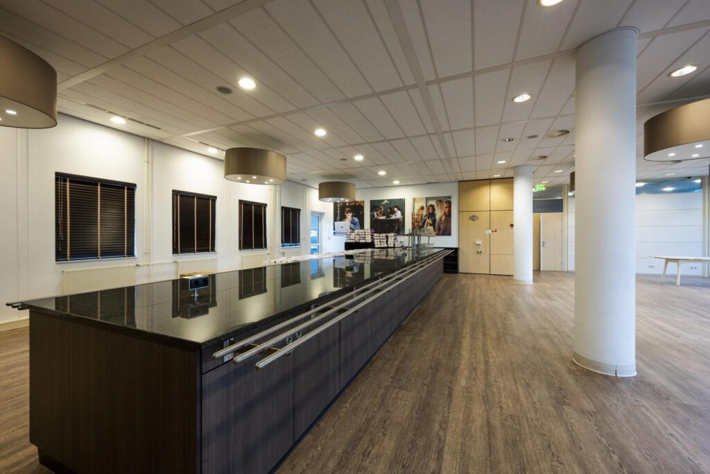 Moderne kantoor- of bedrijfsruimte aan de Paasheuvelweg met een lange balie, houten vloer en plafondverlichting.
