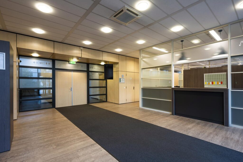 Moderne entreehal van een kantoorpand aan de Paasheuvelweg met een receptiebalie en toiletruimte.