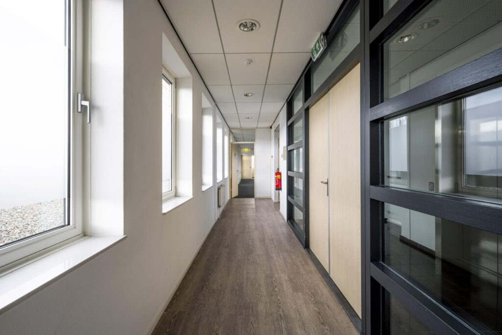 Lichte en moderne kantoorgang aan de Paasheuvelweg met grote ramen en houten vloer.