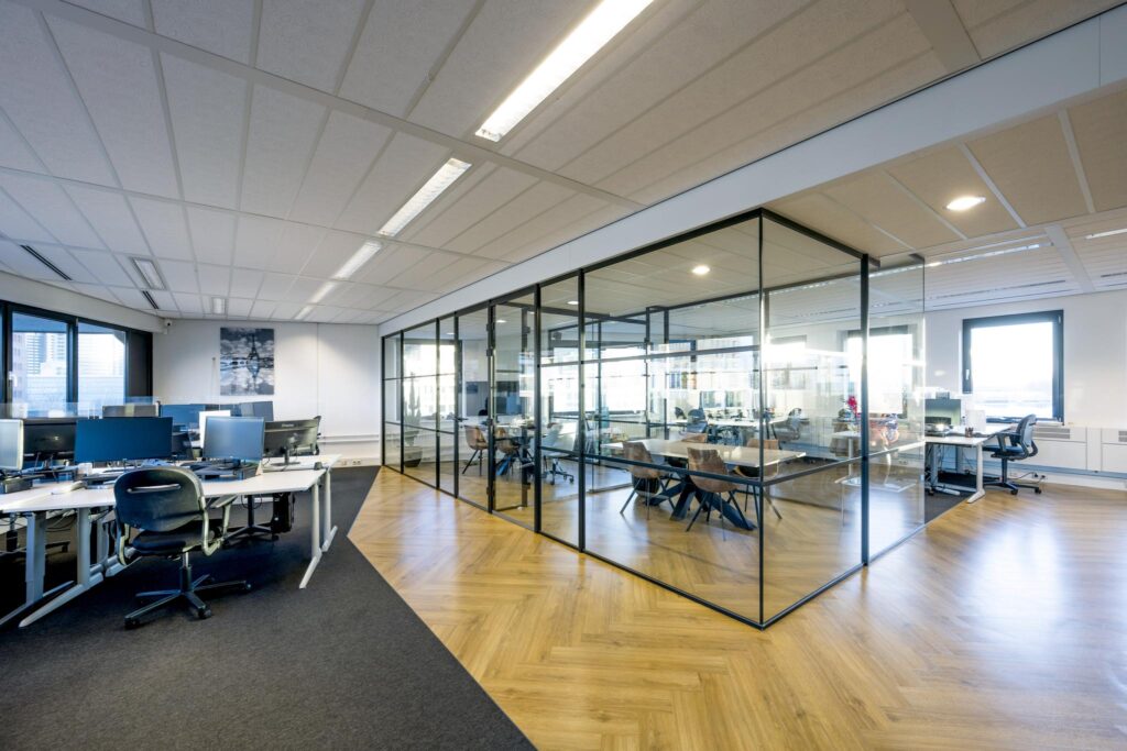 Modern kantoorinterieur aan de Radarweg met open werkplekken en een vergaderruimte met glazen wanden.
