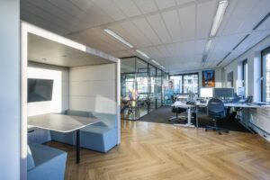 Modern kantoorinterieur aan de Radarweg met flexibele werkplekken, vergaderruimte en zithoek met tv.