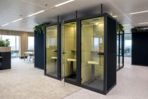 Modern office space at Amstelplein featuring two soundproof focus pods with glass doors and minimalist seating.